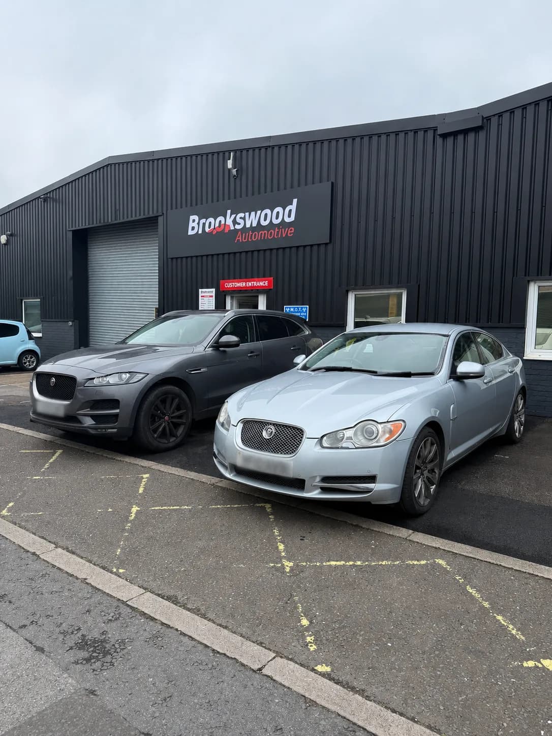 Two Jaguars looked after by Brookswood Automotive, parked outside on an overcast day