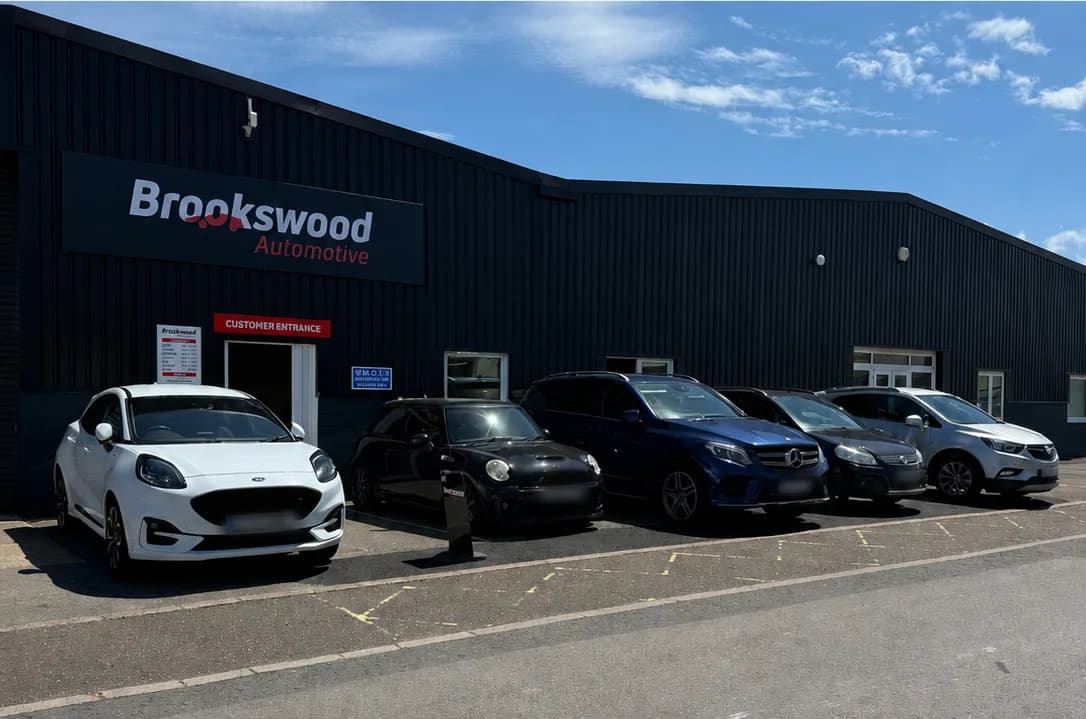 A sunny-day lineup of cars looked after by Brookswood Automotive, including a Ford Puma, Mini, blue Mercedes GLE and silver Vauxhall