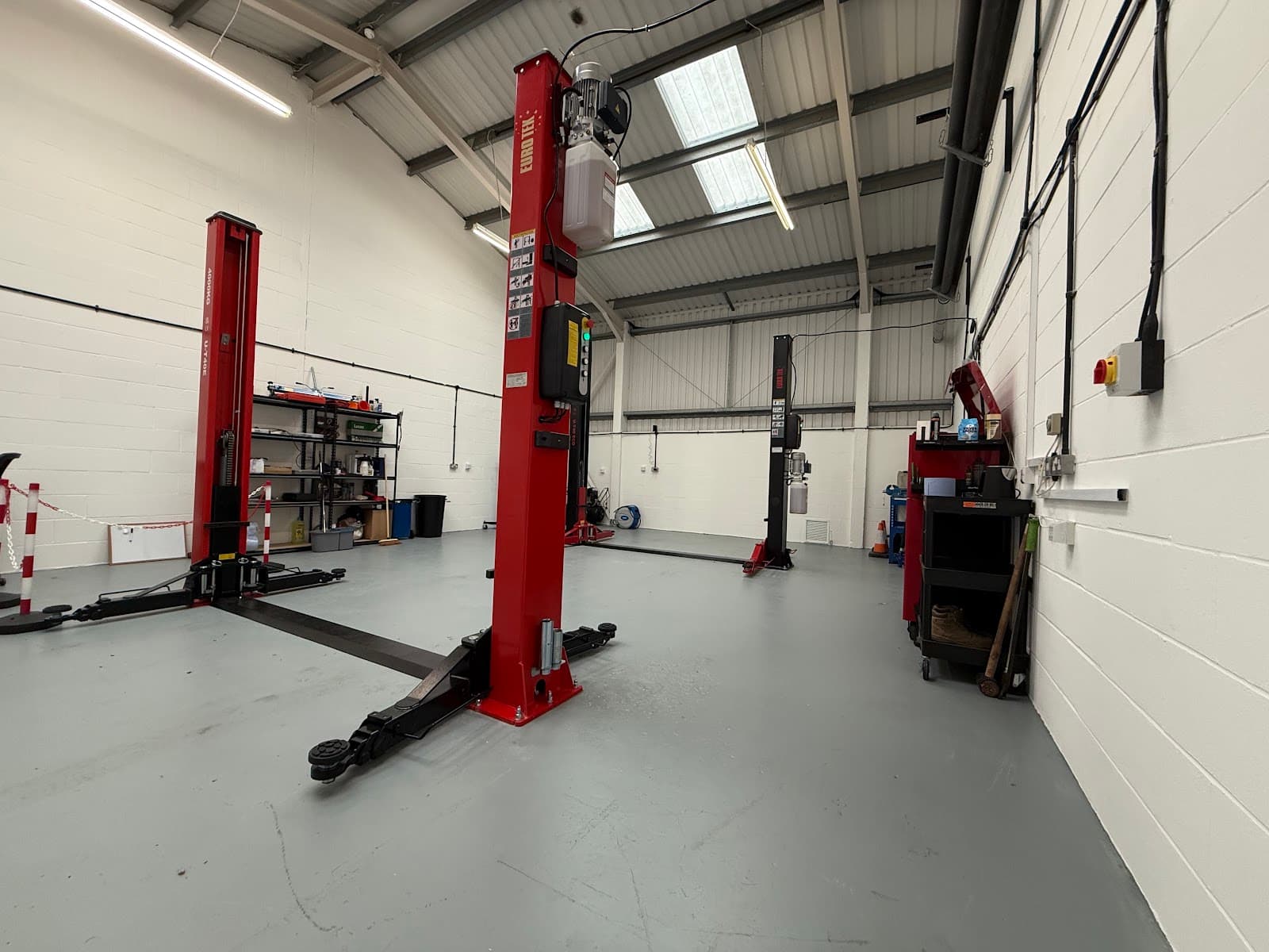 Clean, modern workshop interior at Brookswood Automotive with red hydraulic vehicle lifts