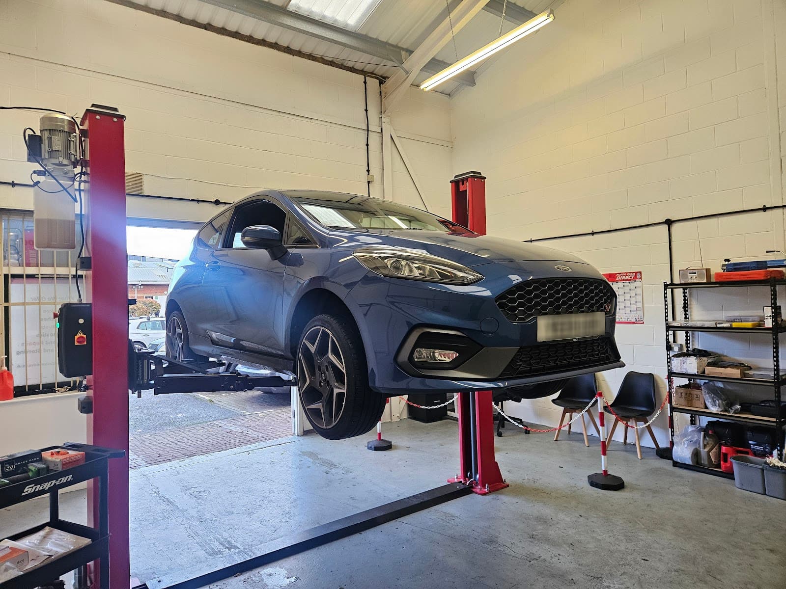 Blue Ford raised on a hydraulic lift for servicing in the Brookswood Automotive workshop