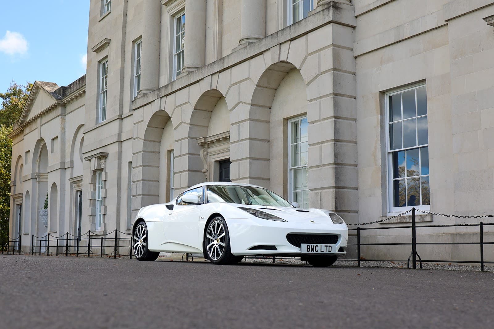 White Lotus sports car cared for by Brookswood Automotive, parked outside a classical stone building